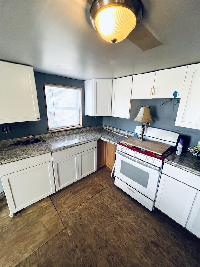 kitchen with white cabinets, gas range gas stove, and dark stone countertops