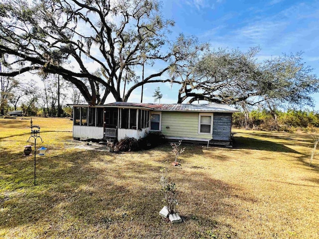 back of house with a sunroom and a lawn