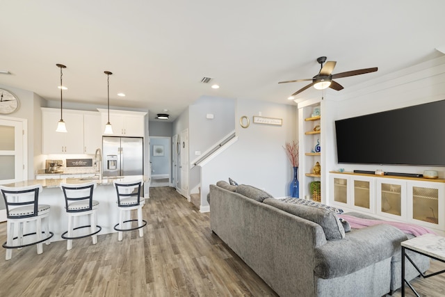 living room featuring hardwood / wood-style flooring, built in features, and ceiling fan