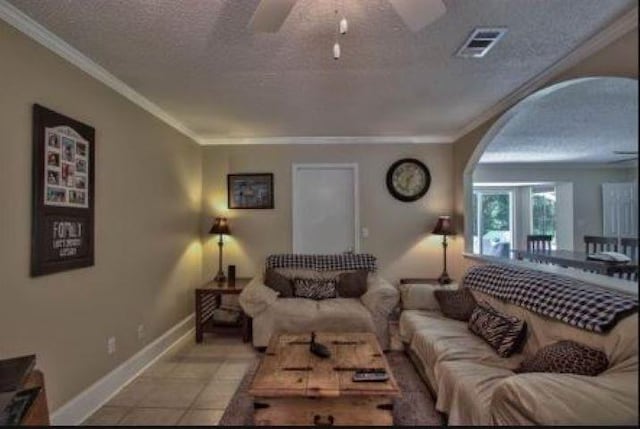 tiled living room featuring ceiling fan, a textured ceiling, and ornamental molding