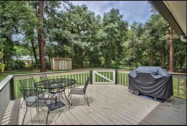 wooden terrace featuring area for grilling and a storage shed