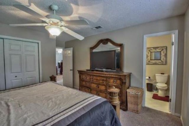 carpeted bedroom featuring ceiling fan, a textured ceiling, ensuite bathroom, and a closet