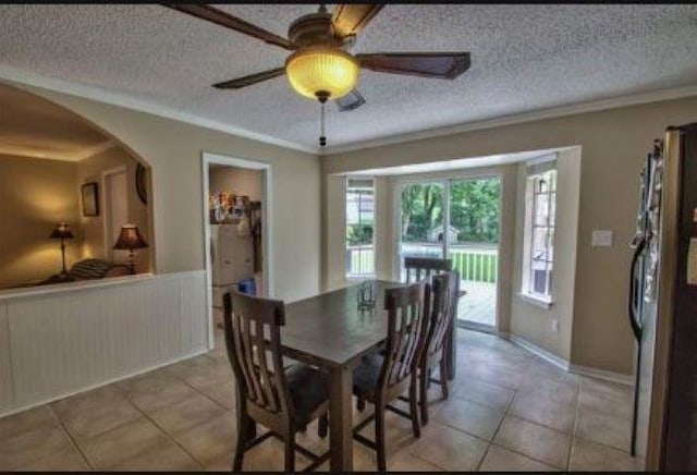 dining space featuring ceiling fan, ornamental molding, light tile patterned floors, and a textured ceiling