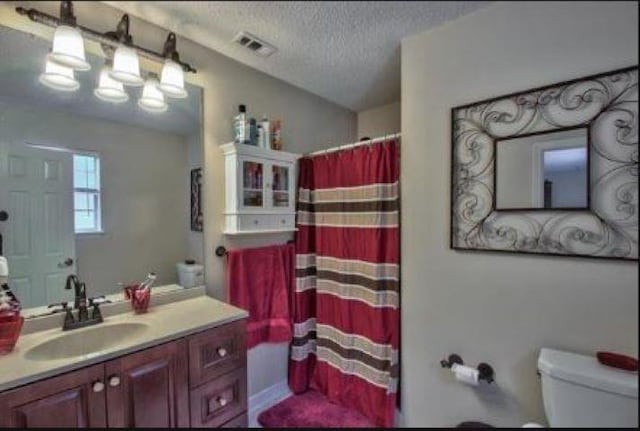 bathroom with a textured ceiling, toilet, and vanity