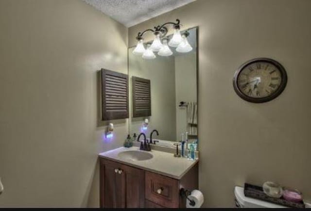 bathroom featuring a textured ceiling, toilet, and vanity