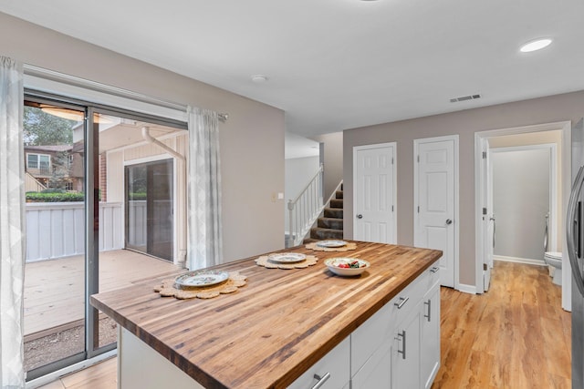 kitchen featuring white cabinets, a kitchen island, light hardwood / wood-style flooring, and butcher block counters