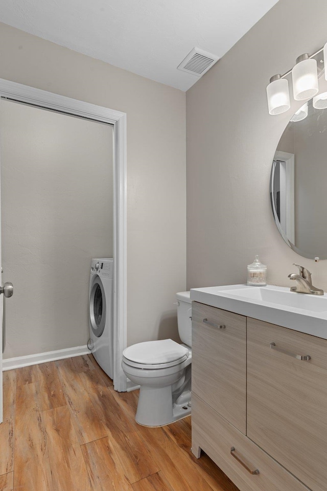 bathroom with hardwood / wood-style flooring, vanity, toilet, and washer / clothes dryer