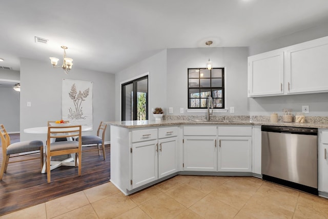 kitchen with a peninsula, a sink, white cabinetry, stainless steel dishwasher, and decorative light fixtures