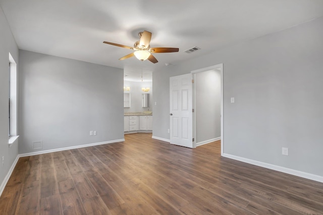 spare room featuring baseboards, visible vents, ceiling fan, and dark wood-type flooring