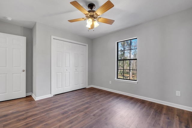 unfurnished bedroom featuring a ceiling fan, a closet, baseboards, and dark wood-type flooring