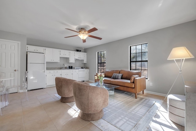 living room with ceiling fan, baseboards, and light tile patterned floors