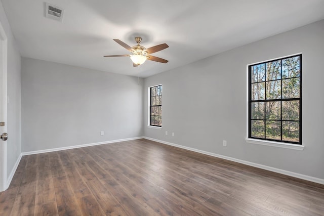 spare room featuring a healthy amount of sunlight, dark wood-style floors, and visible vents