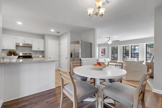 dining space with visible vents, dark wood-style flooring, and ceiling fan with notable chandelier