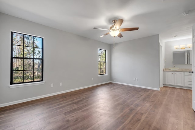 unfurnished bedroom with a ceiling fan, baseboards, wood finished floors, and ensuite bathroom