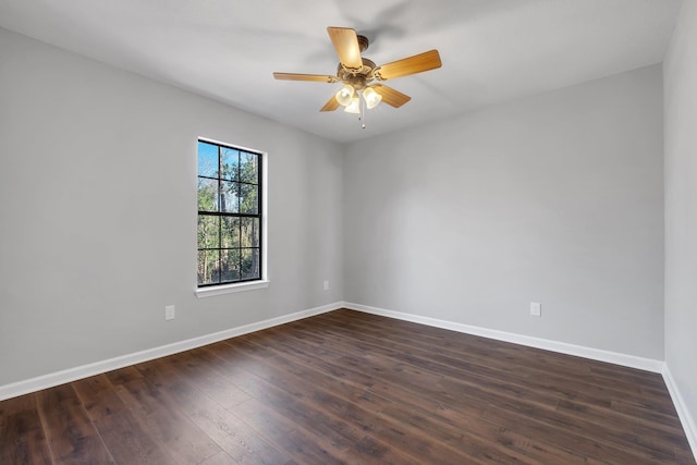 empty room with dark wood-type flooring, a ceiling fan, and baseboards