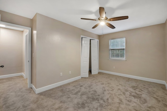 unfurnished bedroom with light carpet, a closet, a ceiling fan, and baseboards