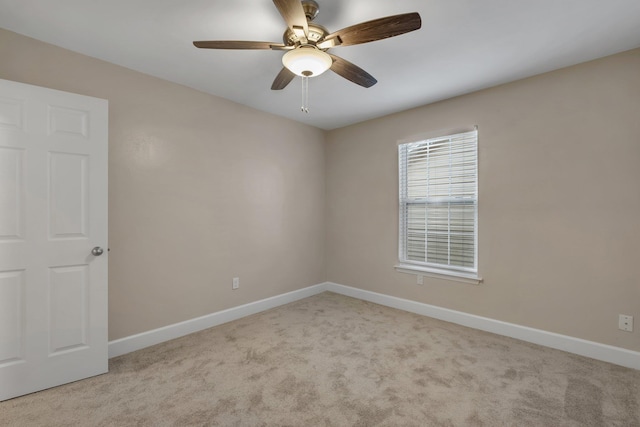 spare room with a ceiling fan, light carpet, and baseboards