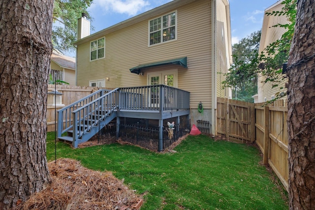 rear view of property with a fenced backyard, a chimney, a lawn, and a wooden deck