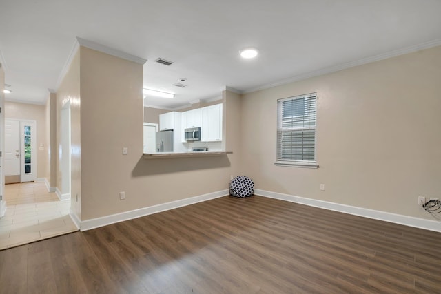 unfurnished room with baseboards, wood finished floors, visible vents, and crown molding