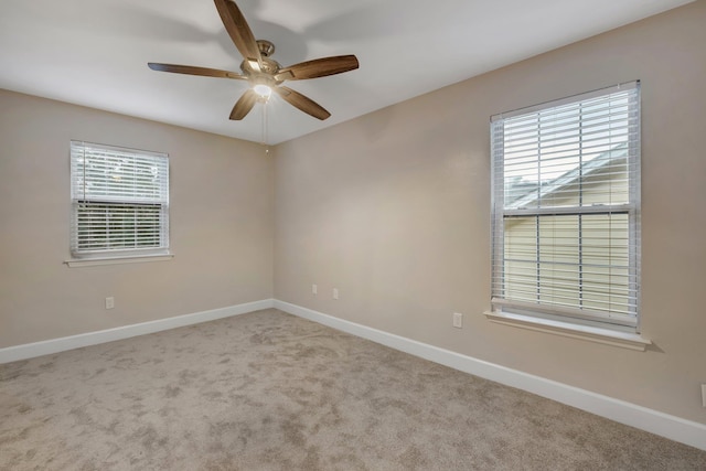 empty room featuring a ceiling fan, light colored carpet, and baseboards