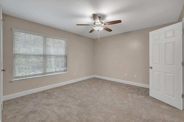 empty room with light carpet, baseboards, and a ceiling fan