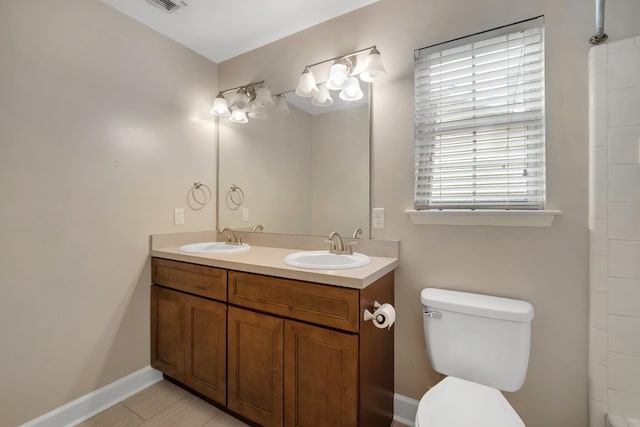 full bathroom with baseboards, a sink, toilet, and double vanity