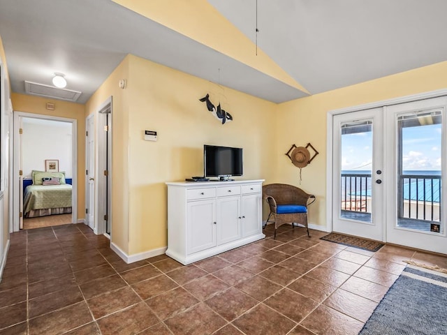 unfurnished living room featuring french doors, dark tile patterned flooring, and vaulted ceiling