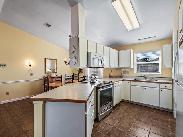 kitchen with lofted ceiling, sink, white cabinets, kitchen peninsula, and stainless steel appliances