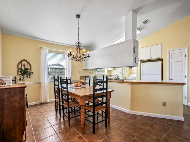 dining space featuring lofted ceiling, dark tile patterned flooring, and an inviting chandelier