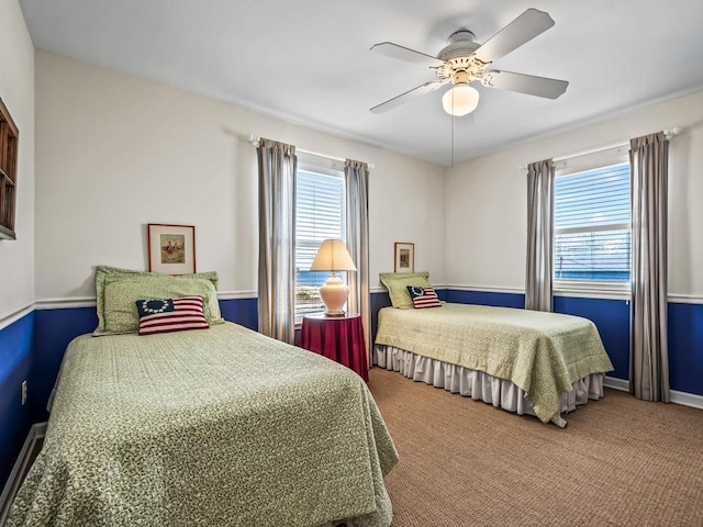 carpeted bedroom featuring multiple windows and ceiling fan