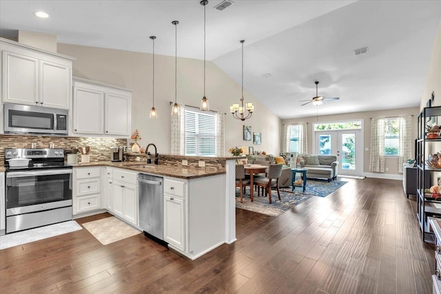 kitchen with white cabinets, dark wood-type flooring, appliances with stainless steel finishes, and dark stone counters