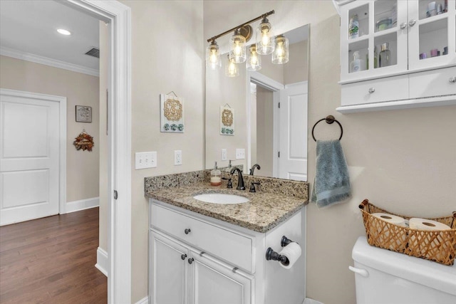 bathroom featuring toilet, vanity, ornamental molding, and hardwood / wood-style flooring