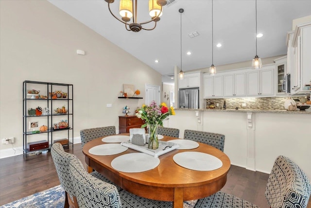 dining area featuring dark wood-type flooring, high vaulted ceiling, and a chandelier