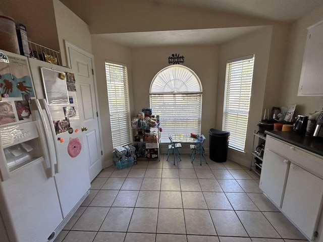 dining space featuring light tile patterned flooring, lofted ceiling, and a healthy amount of sunlight