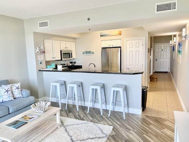 122 Seascape Dr Unit 1406, Destin, FL 32550 - kitchen with stainless steel appliances, a peninsula, a kitchen breakfast bar, and white cabinets