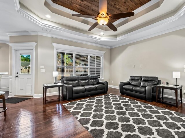 living room featuring a raised ceiling, ceiling fan, and ornamental molding