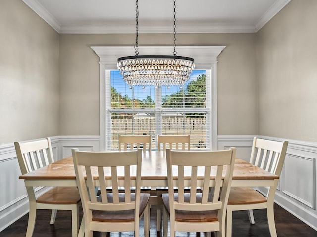 dining room with dark wood-type flooring, ornamental molding, and an inviting chandelier