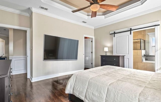 bedroom featuring dark hardwood / wood-style flooring, ornamental molding, a tray ceiling, ceiling fan, and a barn door