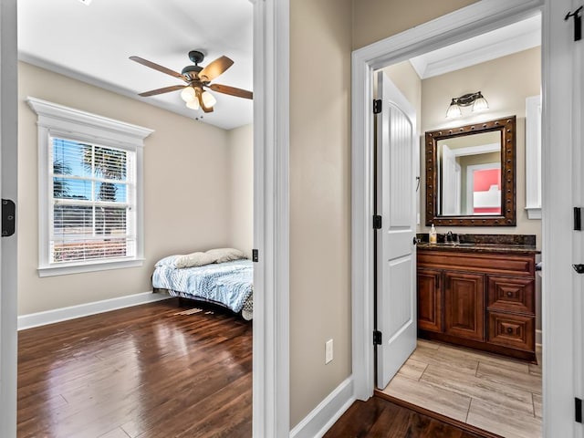 bedroom with light wood-type flooring, ensuite bath, ceiling fan, and sink