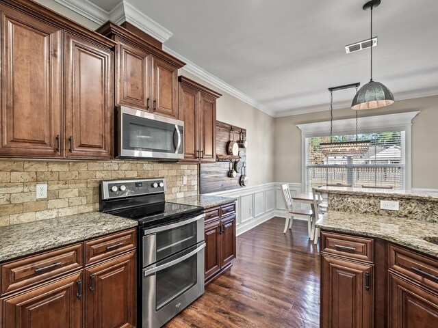 kitchen with stainless steel appliances, light stone counters, hanging light fixtures, and crown molding