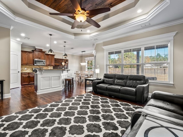 living room featuring a raised ceiling, ceiling fan, dark wood-type flooring, and ornamental molding