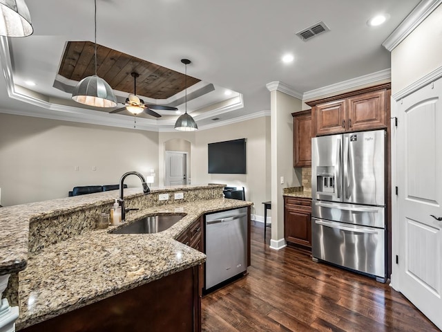 kitchen featuring appliances with stainless steel finishes, a raised ceiling, ceiling fan, sink, and hanging light fixtures