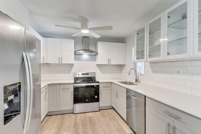 kitchen featuring appliances with stainless steel finishes, sink, wall chimney range hood, and white cabinets