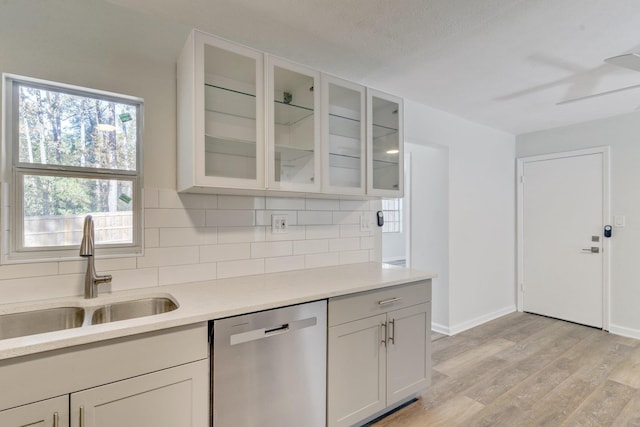 kitchen featuring sink, ceiling fan, tasteful backsplash, stainless steel dishwasher, and light wood-type flooring