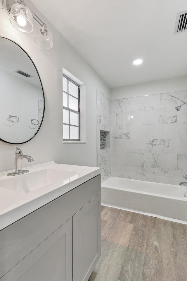 bathroom with tiled shower / bath combo, vanity, and hardwood / wood-style flooring