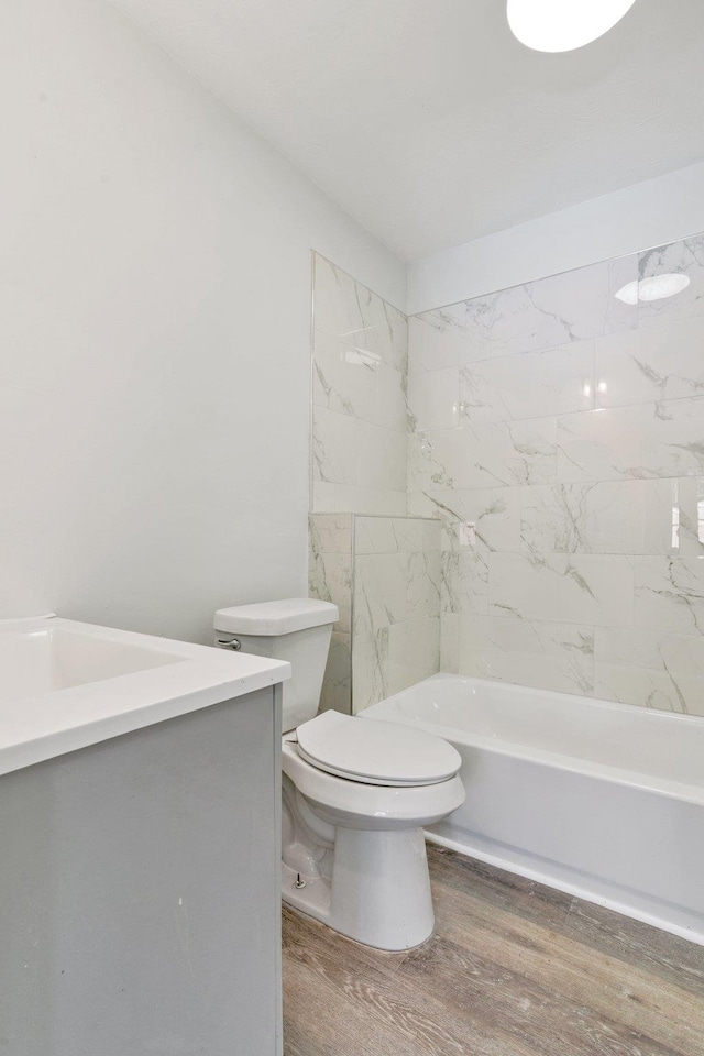 full bathroom featuring vanity, tiled shower / bath, wood-type flooring, and toilet