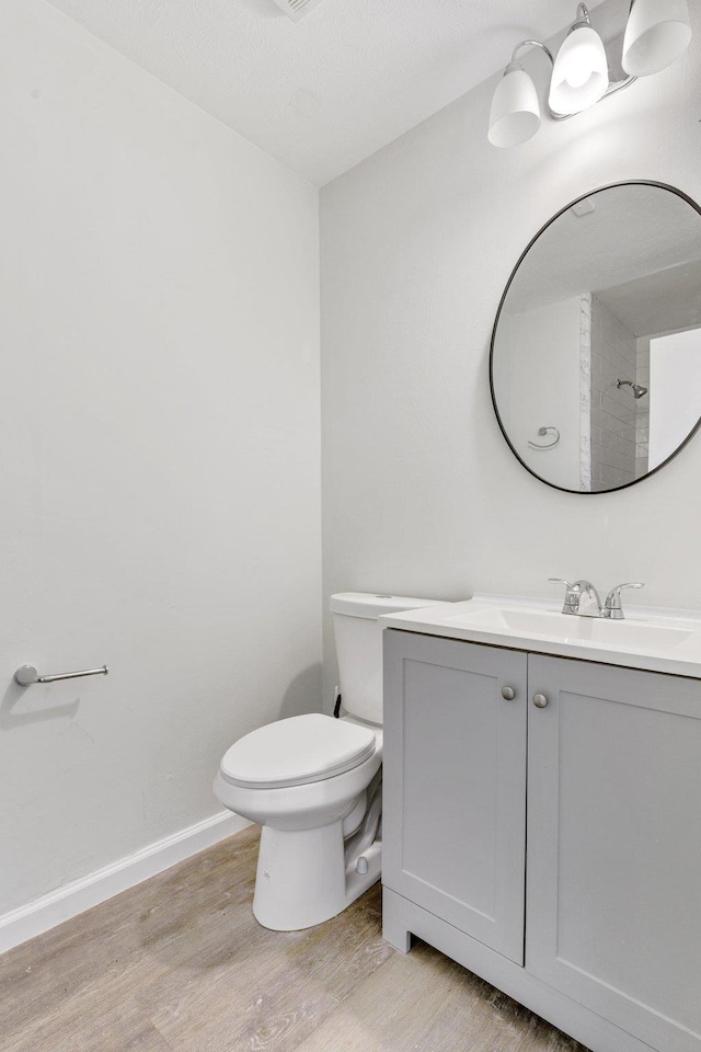 bathroom with walk in shower, wood-type flooring, toilet, and vanity