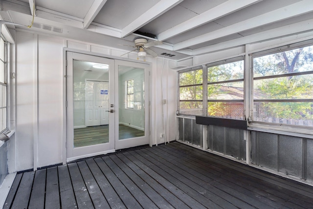 unfurnished sunroom with beamed ceiling, ceiling fan, and a wealth of natural light