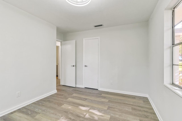 unfurnished bedroom with multiple windows and light hardwood / wood-style flooring