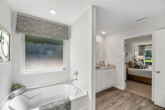 bathroom with a tub to relax in, vanity, and hardwood / wood-style floors